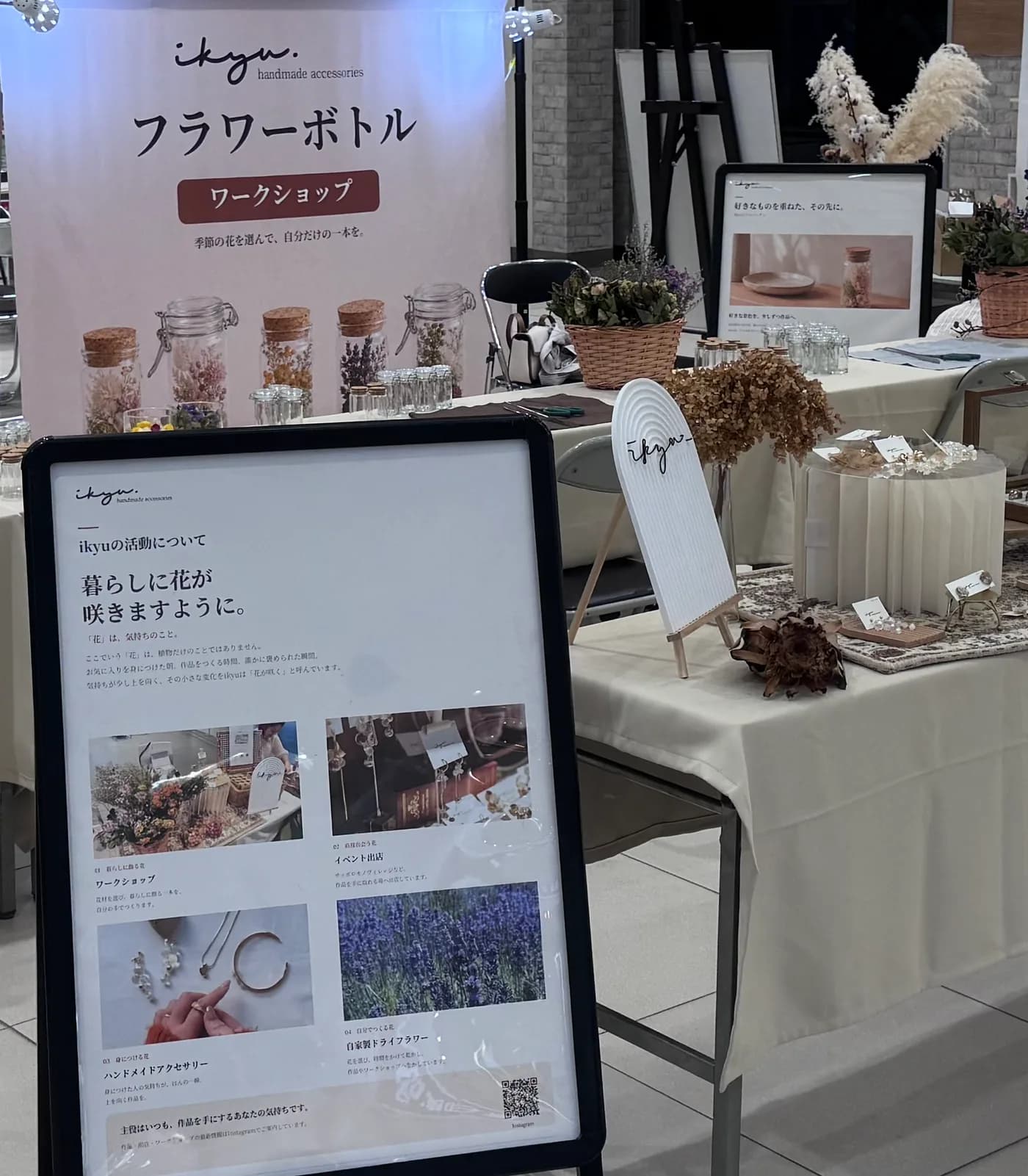 アリオ札幌のikyuブース。フラワーボトルワークショップのバナーの下に、花材の瓶が並ぶ体験テーブルとドライフラワーの展示